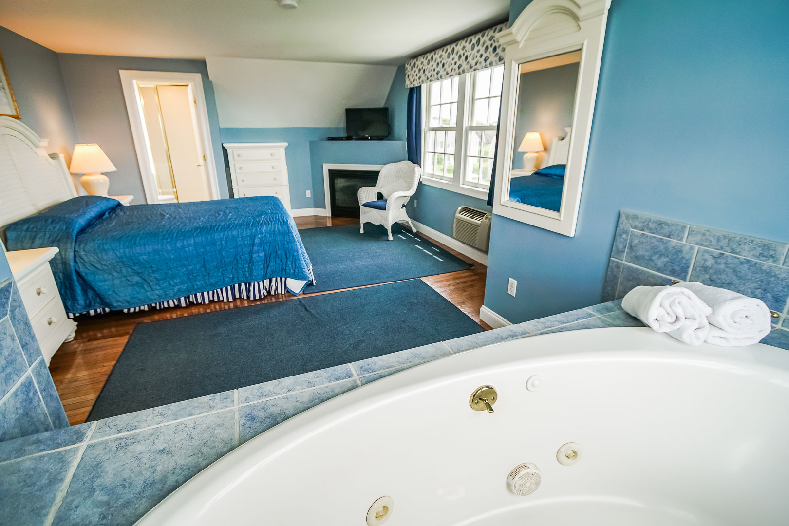 A spacious master bedroom with a jacuzzi tub at VRI's Beachside Village Resort in Massachusetts.